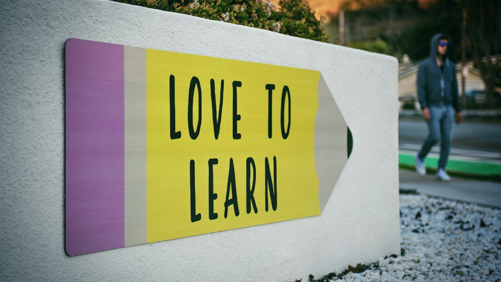 love to learn pencil signage on wall near walking man