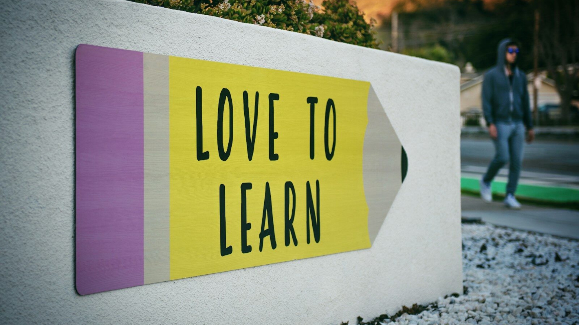 love to learn pencil signage on wall near walking man