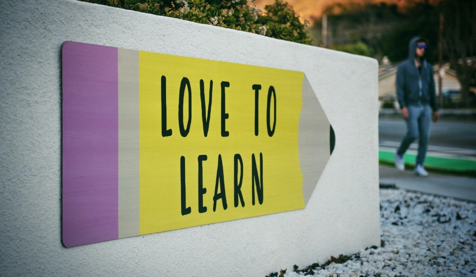 love to learn pencil signage on wall near walking man